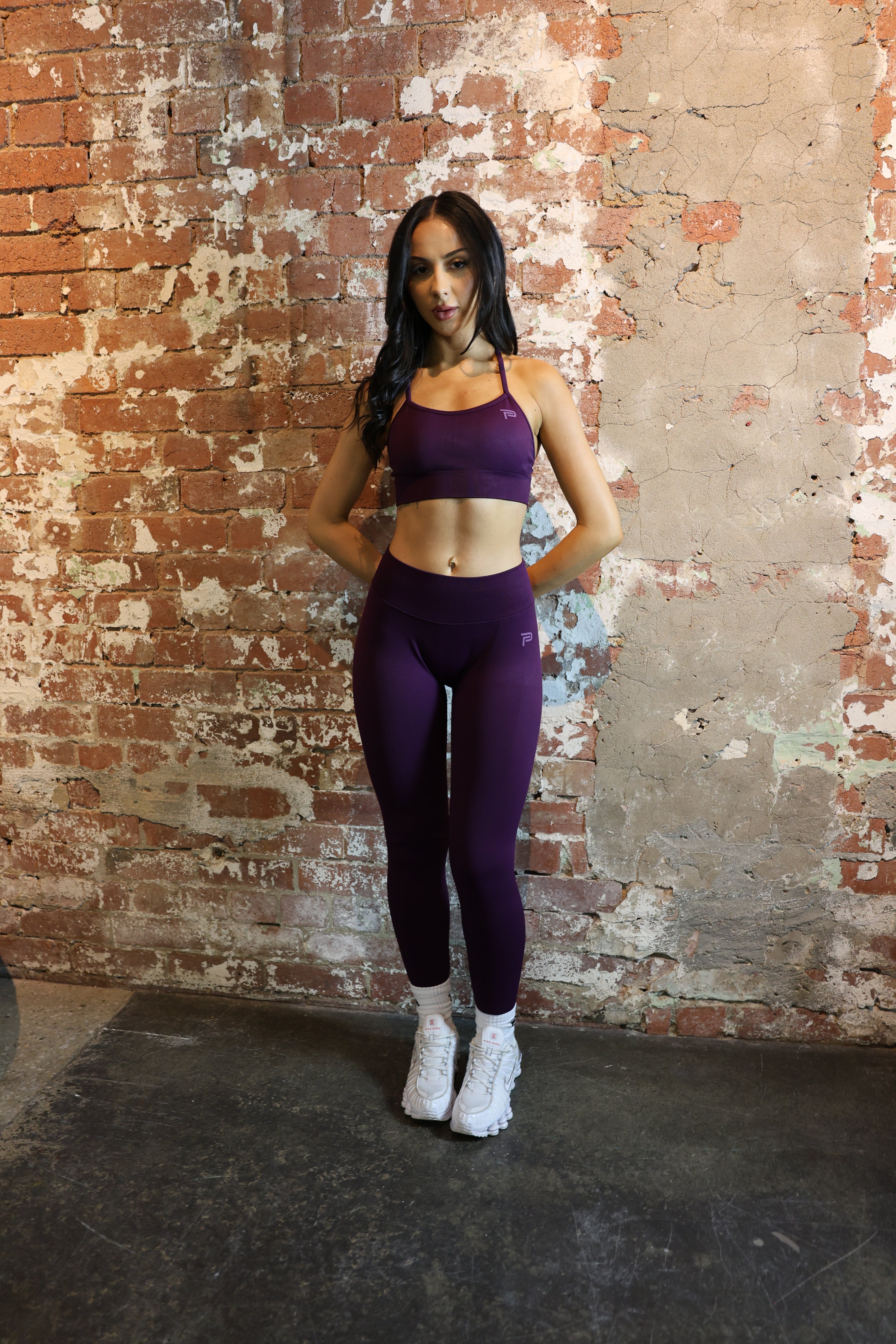 Woman in purple athletic wear lying on a textured brick floor